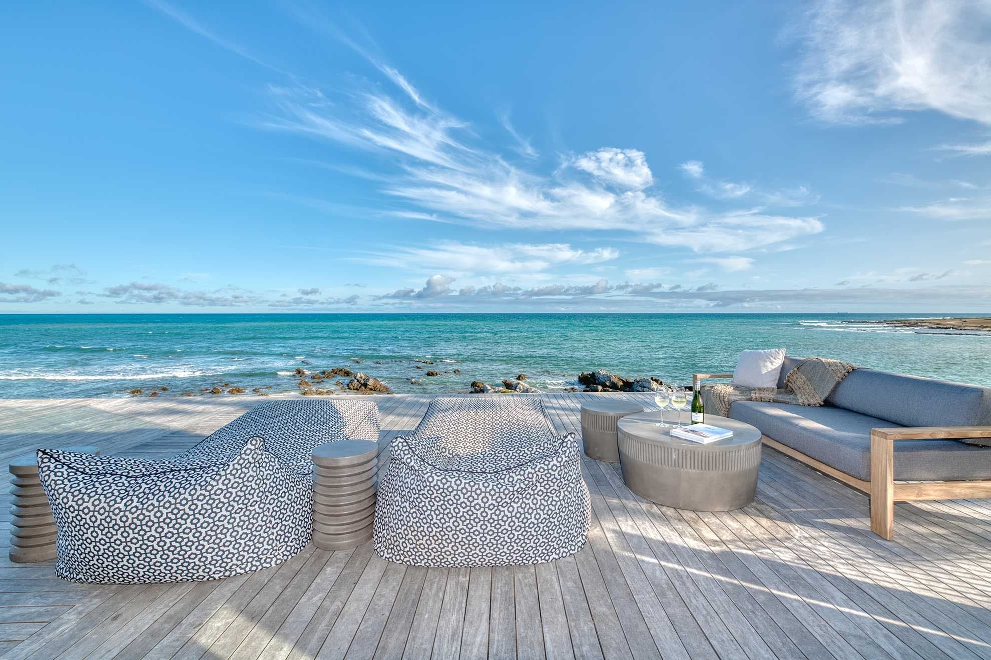A wraparound deck with loungers, a sofa and wine looking straight out to sea