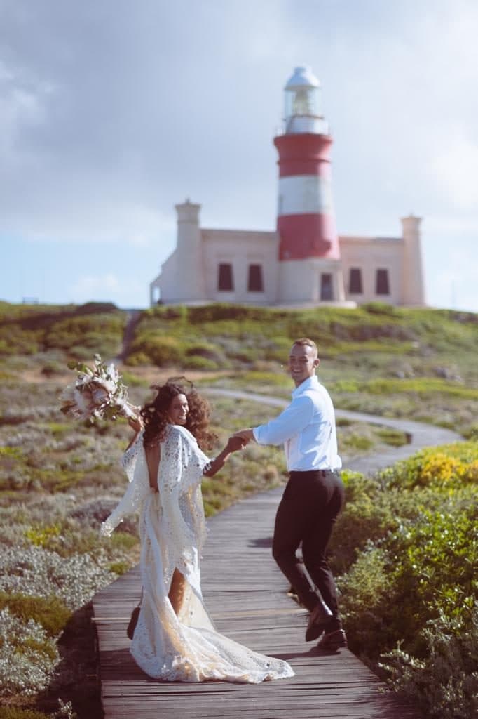 A couple in wedding attire on the boardwalk to the Cape Agulhas lighthouse