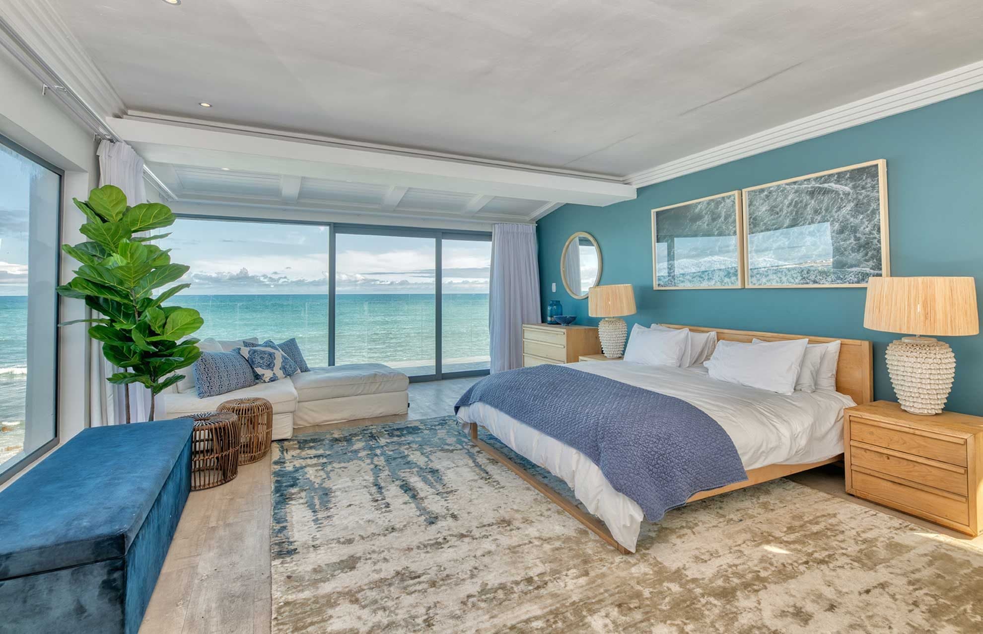 A king bedroom with a teal accent wall and glass doors opening directly onto the Atlantic