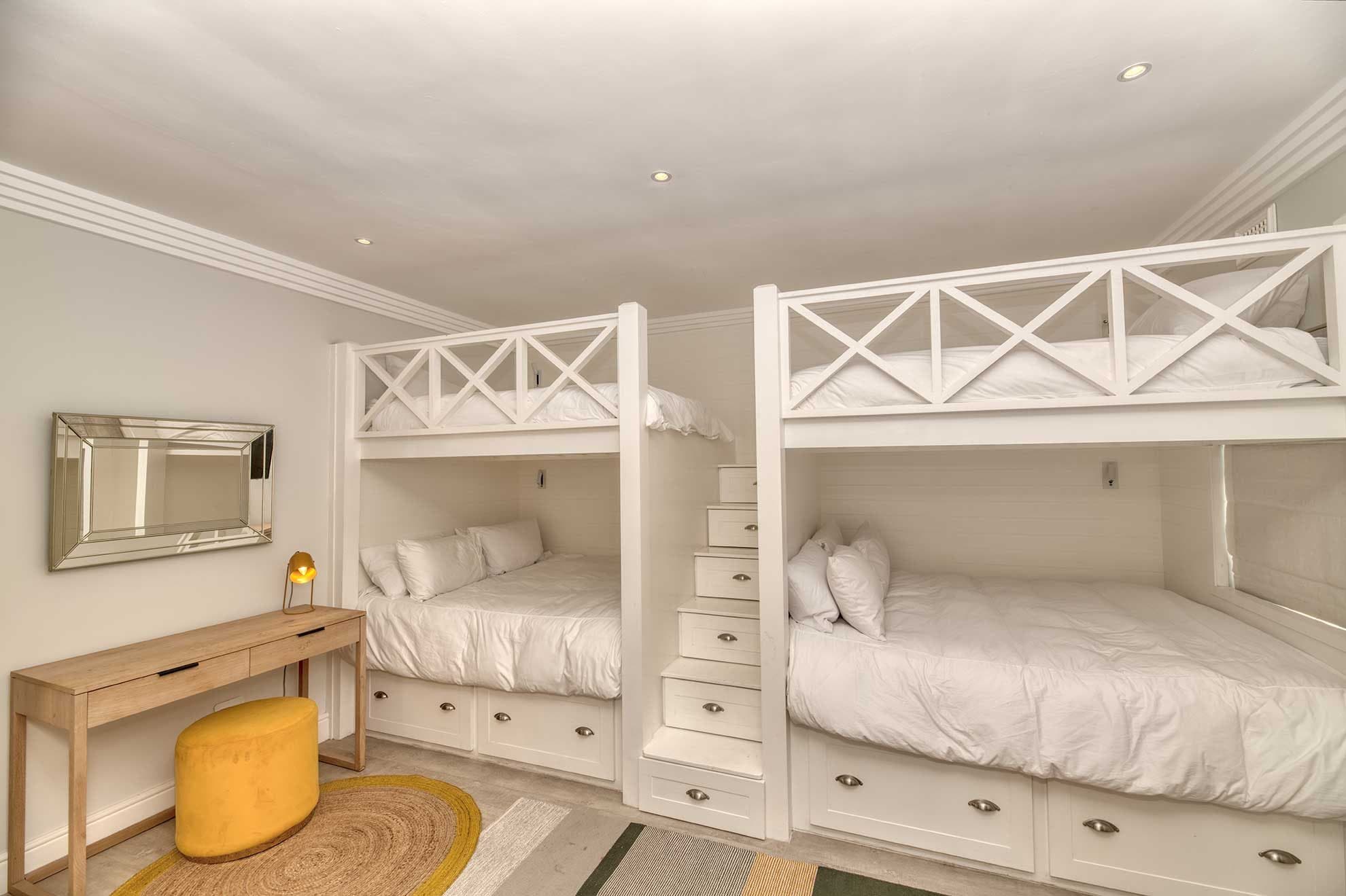 A built-in bunk room with two double bunk beds and a storage staircase between them