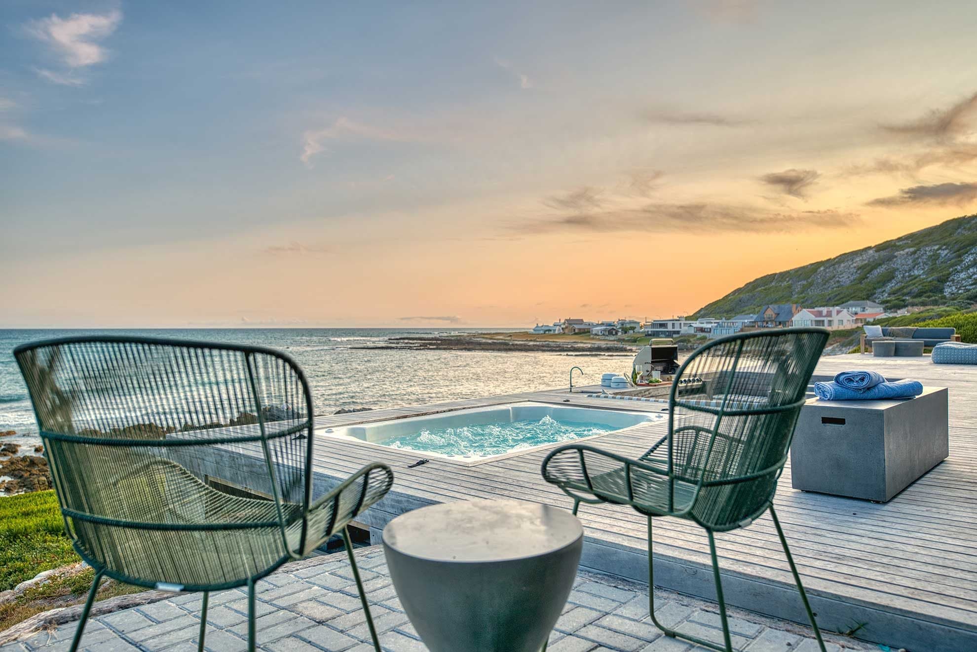 Sunset over the private jacuzzi deck and coastal village at L'Agulhas